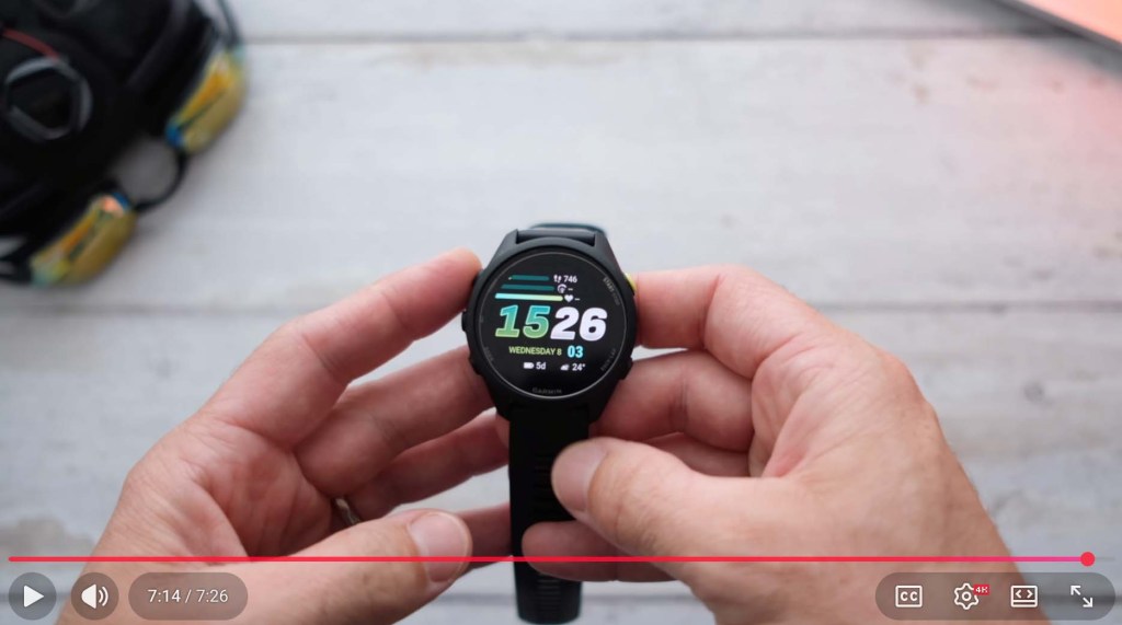 A person holding a black smartwatch displaying the time '15:26' and the date 'Wednesday 03'.